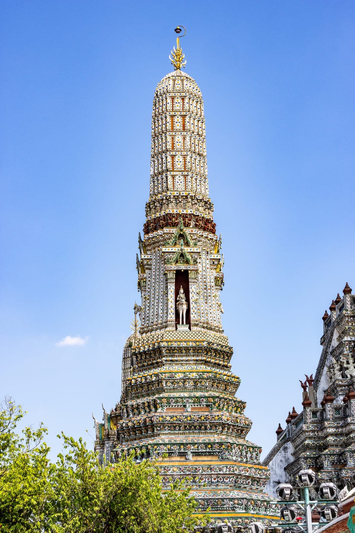 The tall porcelain-encrusted central prang of Wat Arun against a blue sky